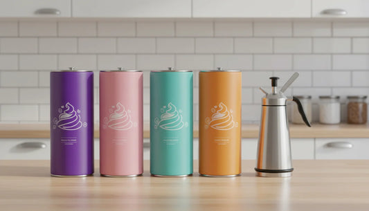 Colorful flavored nitrous oxide charger tanks next to a stainless steel whipped cream dispenser on a kitchen counter